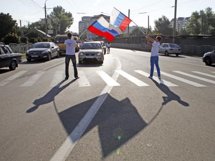 Волонтеры поздравляют автомобилистов с днем флага. На снимке: мужчины с российским флагом в руках.