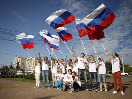 Волонтеры поздравляют автомобилистов с днем флага. На снимке: люди с российским флагом в руках.