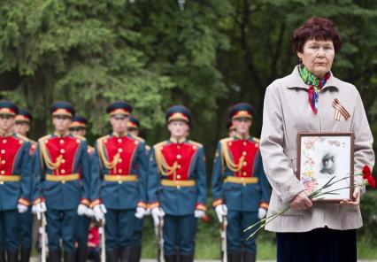 Парад победы в Екатеринбурге. На снимке: женщина с портретом и цветами в руках на фоне солдат.