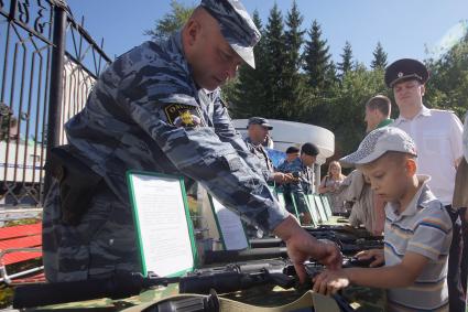 Традиционный праздник силовых структур `Служба дни и ночи` в Екатеринбурге. На снимке: экспозиция с оружием, сотрудник ОМОНа показывает ребенку оружие.