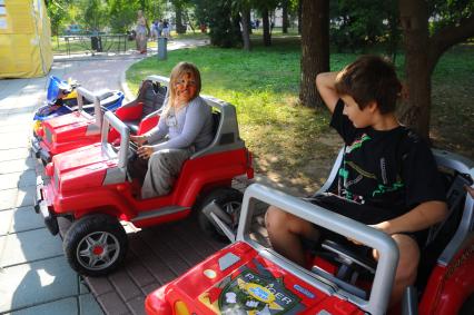 Сад имени Н.Э. Баумана. На снимке: мальчик и девочка на детских электромобилях.
