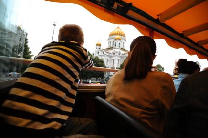 Двухэтажный автобус возит туристов по центру Москвы. На снимке: туристы проезжают Храм Христа Спасителя.