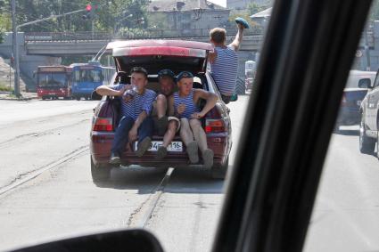 Празднование дня ВДВ в Казани. На снимке: В багажнике автомобиля по дороге едут трое мужчин.