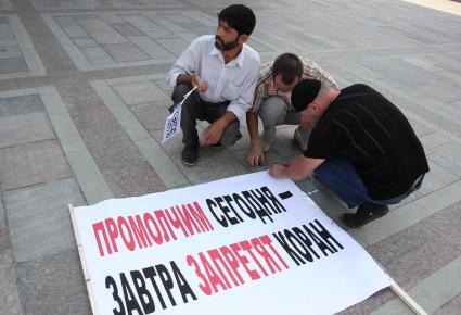 Митинг мусульман против произвола полиции. Площадь театра Камала. Казань. На снимке: Люди прикрепляют плакат с лозунгом: `Промолчим сегодня - завтра запретят коран`.