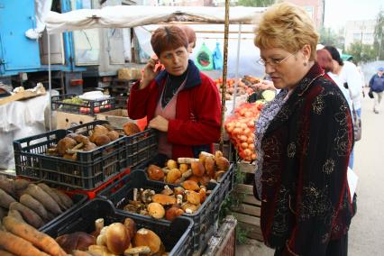 Рынок обощей. На снимке: Женщина покупает грибы на рынке.