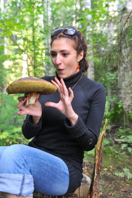 Девушка собирает грибы в лесу.