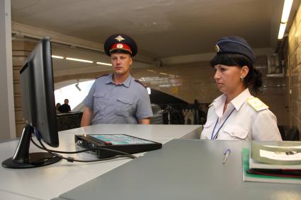 Полицейские в метро проводят операцию `Антитеррор`. На снимке: Полицейский и сотрудница охраны метро смотрят на экран компьютера.