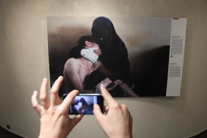 Фотовыставка `World press photo 2012`. На снимке: Посетитель выставки фотографирует на телефон Iphone работу Самуэля Аранда.