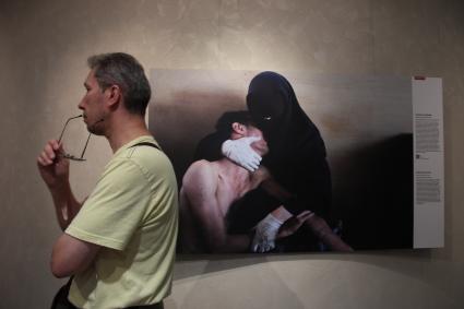 Фотовыставка `World press photo 2012`. На снимке: Мужчина на фоне одной из работ.