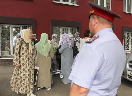 Мусульманские женщины в хиджабах на фоне полицейского.