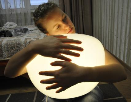 Девушка обнимает руками энергосберегающий светильник.