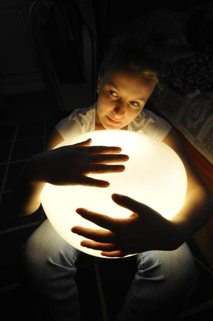 Девушка обнимает руками энергосберегающий светильник.
