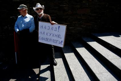 В Калининграде прошел согласованный с властями митинг в поддержку Московского `Марша миллионов`. На снимке: Два мужчины стоят на лестнице, один из них держит в руках плакат: `Назад! На кухню, бандерлоги!..`