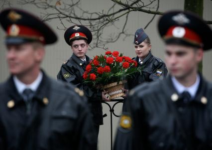 Полицейские мужчина и женщина с корзиной цветов в руках.