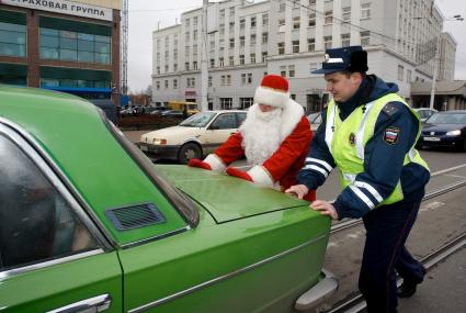 Полицейский помогает деду морозу отбуксировать автомобиль.