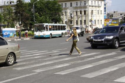 Девушка переходит автомобильную дорогу по пешеходному переходу.