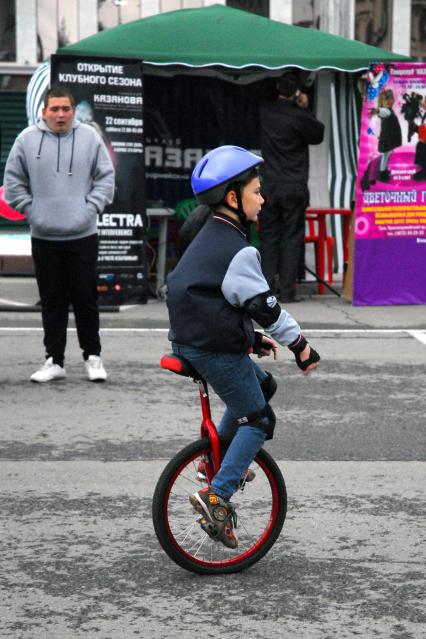 Мальчик едет на одноколёсном велосипеде.