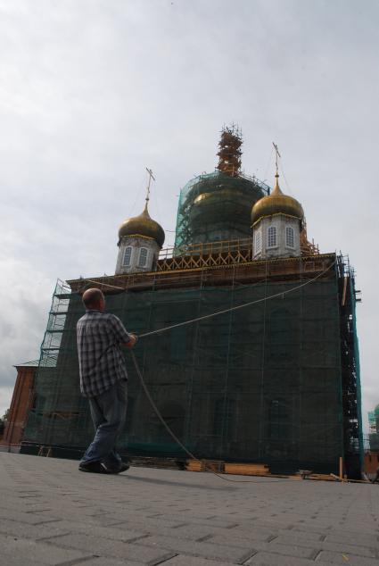 Ремонт Успенского собора на территории тульского кремля. Рабочий тянет канат с доской на фоне собора.