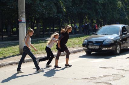 Школьники перебегают дорогу по пешеходному переходу.