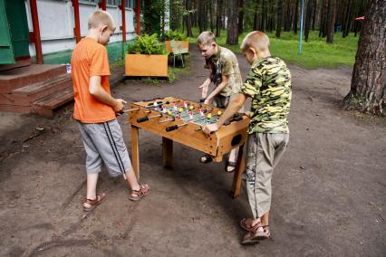 Дети играют в настольный футбол в детском лагере отдыха.