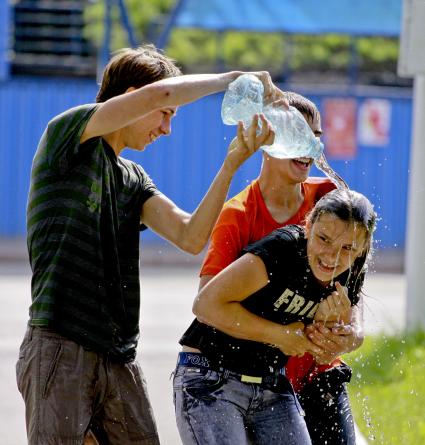 Подростки обливают водой девушку.