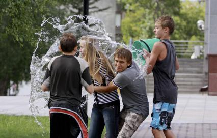 Подростки обливают водой девушку.