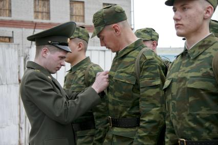 В краевом призывном пункте офицер поправляет форму на новобранце.