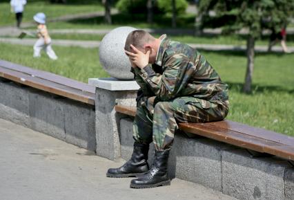 Военный сидит обхватив голову руками.