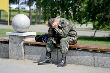 Военный сидит обхватив голову руками.