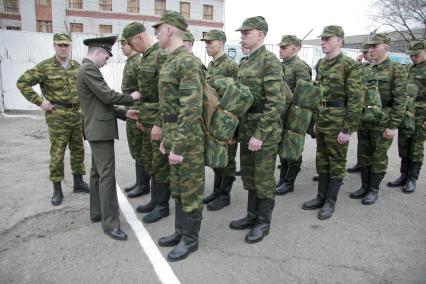 В краевом призывном пункте офицер поправляет форму на новобранце.