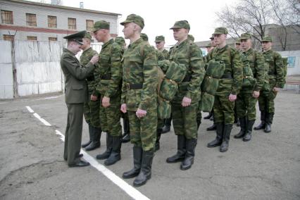 В краевом призывном пункте офицер поправляет форму на новобранце.