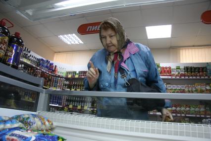 Женщина выбирает пельмени в социальном магазине для пенсионеров.