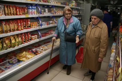 Женщины выбирают продукты в социальном магазине для пенсионеров.