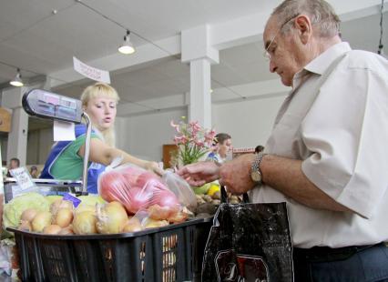 Женщина торгует овощами на рынке.