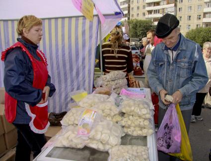 Торговая точка на рынке по продаже замороженных продуктов. На прилавке лежат пельмени в пакетах.