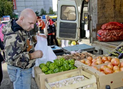 Покупатель выбирает овощи на рынке.
