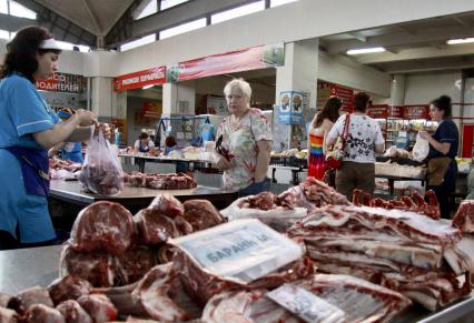 Женщина торгует на рынке мясом.