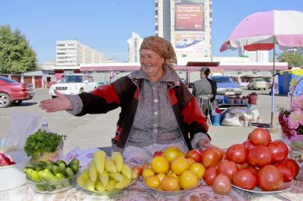 Женщина торгует овощами на открытом рынке.