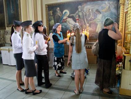 Девушки-курсанты юридического института ставят свечи в Покровском соборе Барнаула.