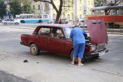 Женщина ремонтирует автомобиль.