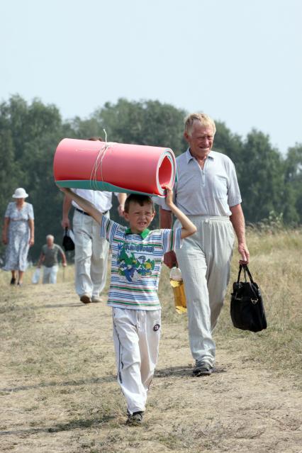 Зрители поднимаются на гору Пикет в селе Сростки, Алтайского края, где проходят Шукшинские чтения. На снимке: мальчик с полиуретановым туристическим ковриком.