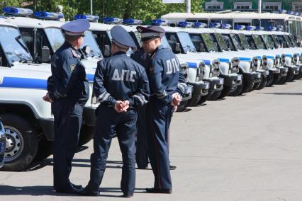 Открытый общегородской развод полицейских нарядов. Сотрудники ДПС на фоне большого количества служебных полицейских автомобилей УАЗ.