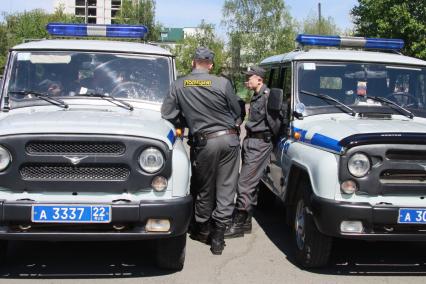 Открытый общегородской развод полицейских нарядов. Две машины УАЗ рядом с которыми стоит группа полицейских.