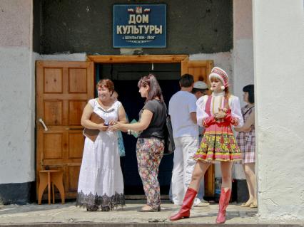 Дом культуры в селе Шульгин Лог. Девушка в псевдонародном с короткой юбкой костюме стоит на крыльце.