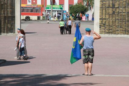 Десантник с флагом ВДВ отдает честь у мемориала.