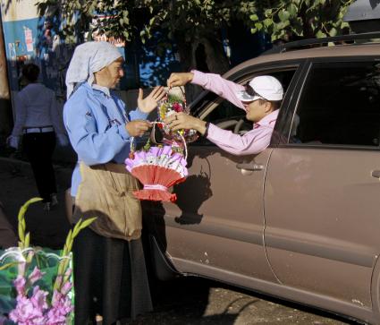 Цветочный рынок. Мужчина покупает букет цветов не выходя из автомобиля.