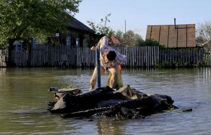 Летний паводок на реке Обь, мужчина пьет воду из колонки. Вокруг все затоплено водой.