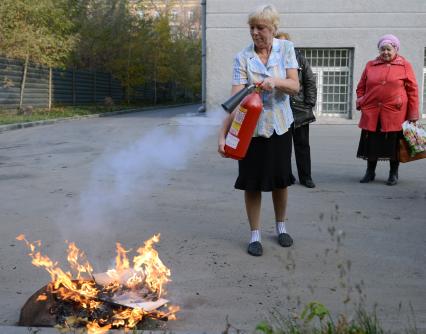 МЧС проводит тренировку по тушению пожара и ликвидации возгораний. На снимке: женщина тушит пламя из огнетушителя.