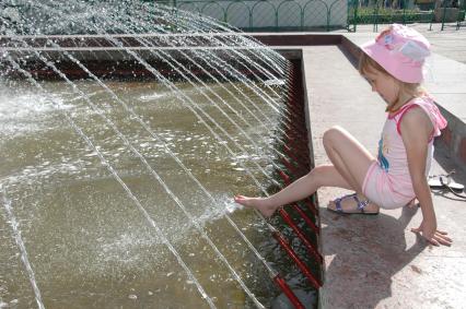 Девочка играет в фонтане с водой.