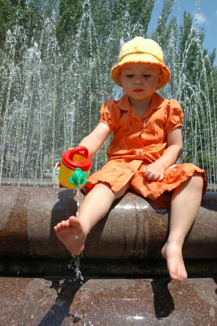 Девочка играет в фонтане с водой.